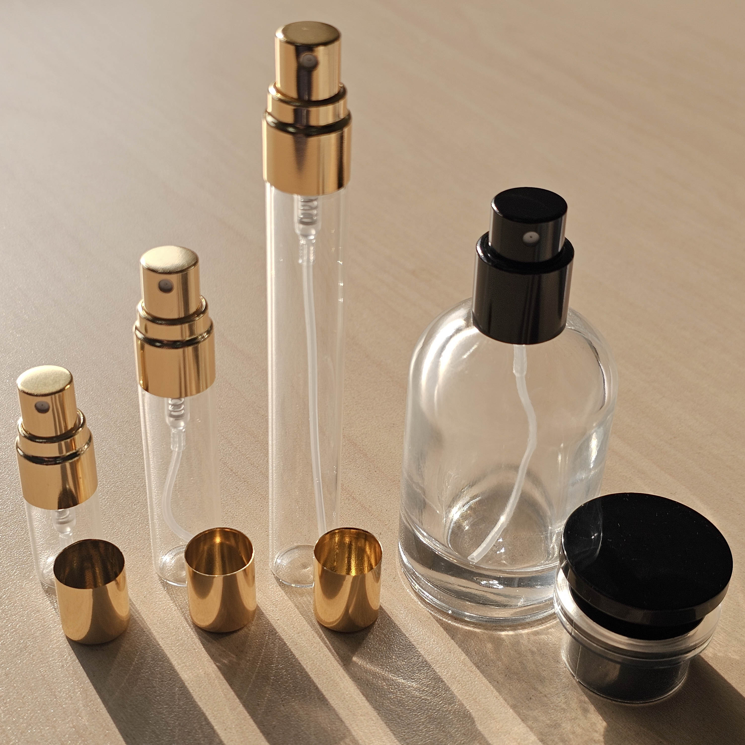 Atelier Elemental decant vial sizes with their caps off: 2 ml, 5 ml and 10 ml gold-cap sprayers beside the 30 ml bottle